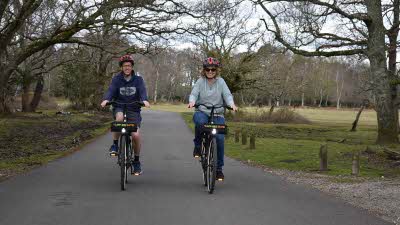 Man and woman wearing helmets on bikes