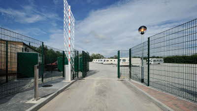 Entrance to caravan storage facility with barrier raised and green railings