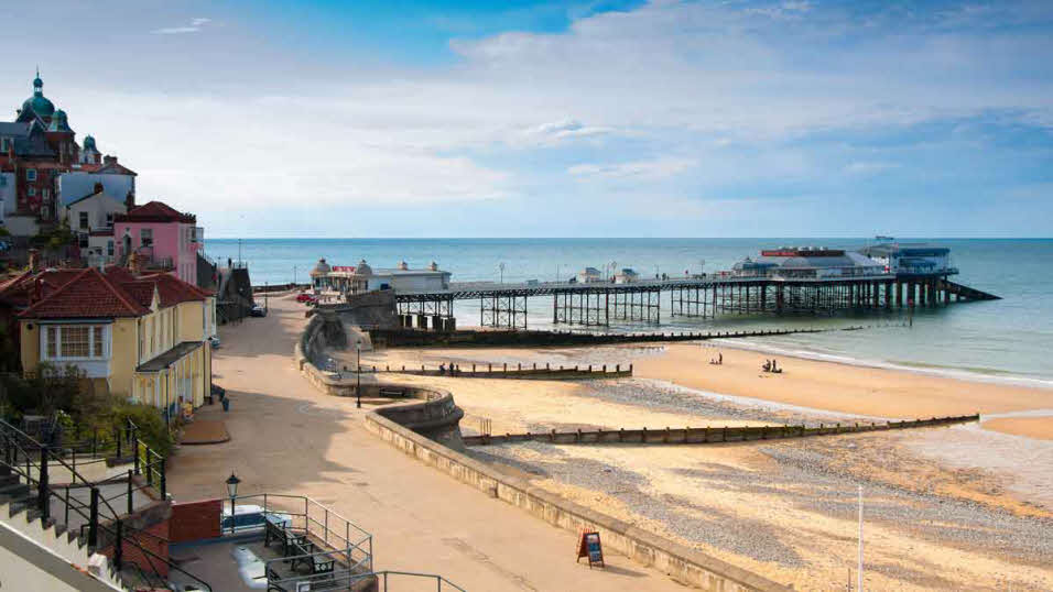 Sunny day at quiet and sandy Cromer Beach and Cromer Pier in Norfolk