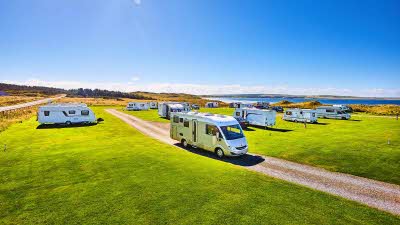 Dunnet Bay campsite with caravans and motorhomes parked on cut grass overlooking bay