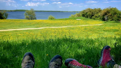 People wearing walking boots, sitting in grassy landscape