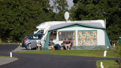 Motorhome with awning and two campers in camper chairs