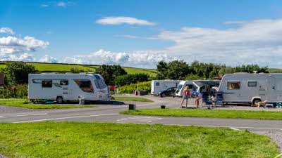 Family of three outside their caravan on a sunny day